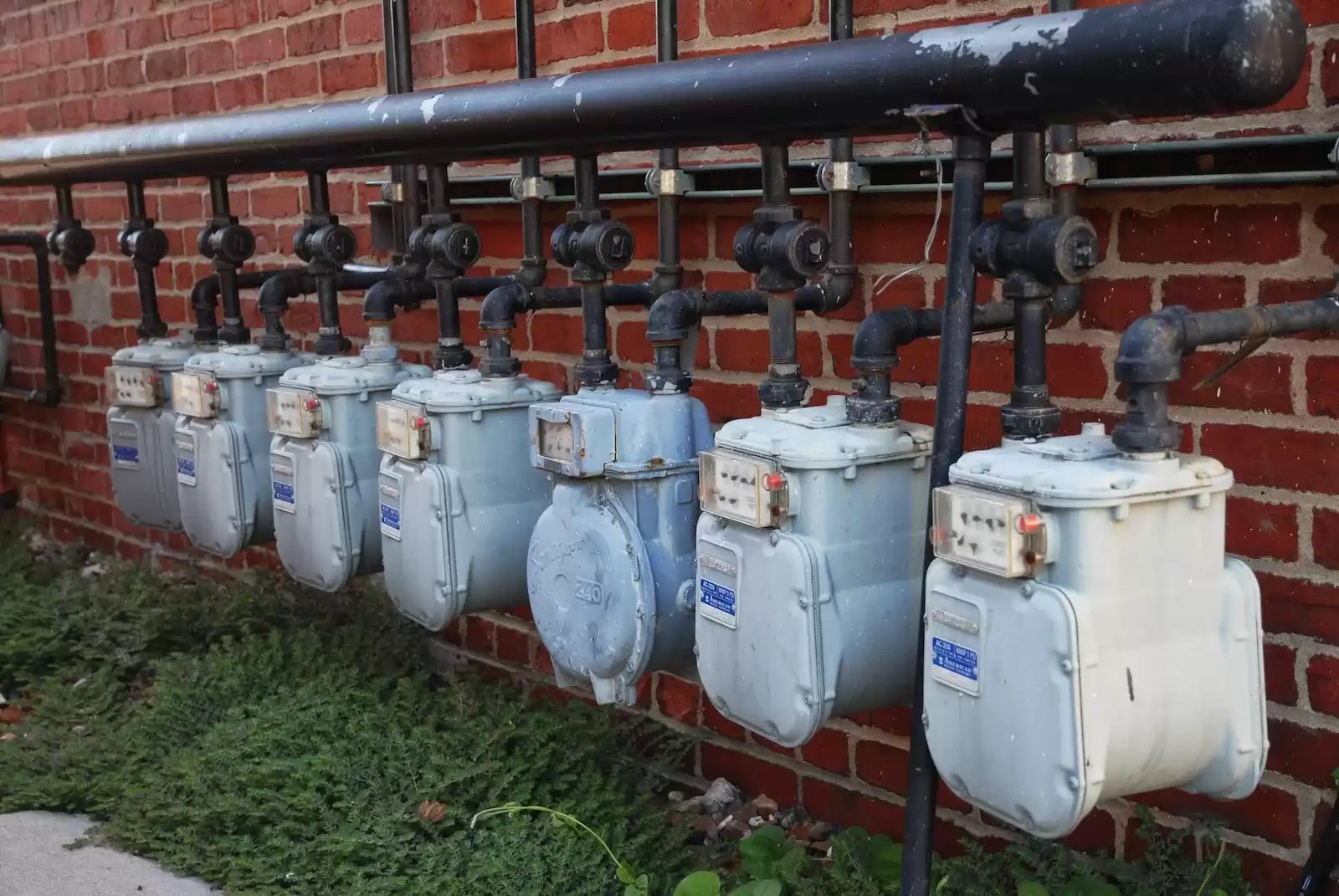 a row of water meters next to a brick wall